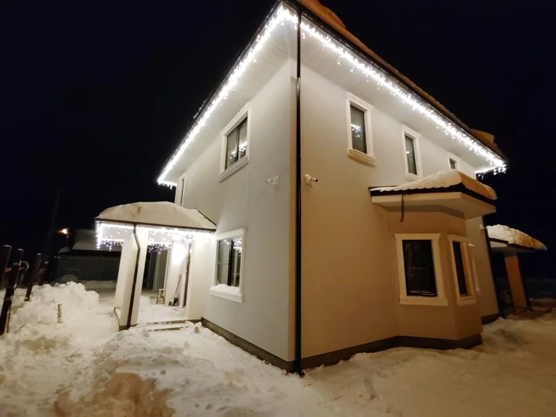 Белый фасад и зимний свет. Световой контур кровли и бахрома над входом.